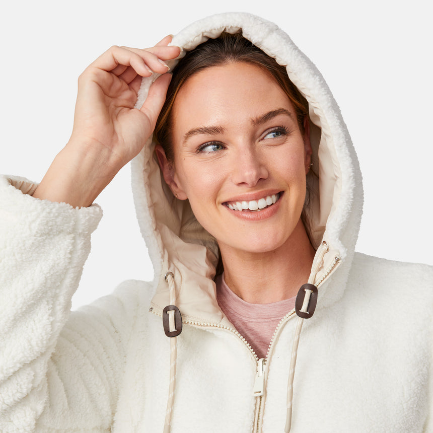 [Emily is 5'9" wearing size S.] Women’s Free Country cream-colored quilted hooded jacket with full-zip closure, drawstring hood, and dual hand pockets—reversible to cozy sherpa for versatile styling and added cold-weather comfort. Styled with jeans for a relaxed, outdoorsy look.