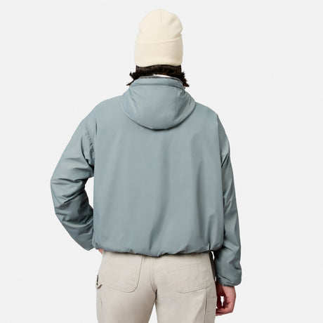 A person wearing the Free Country Women’s Bomber Windshear Jacket in light gray, beige pants, and a cream beanie stands with their back to the camera against a plain white background.