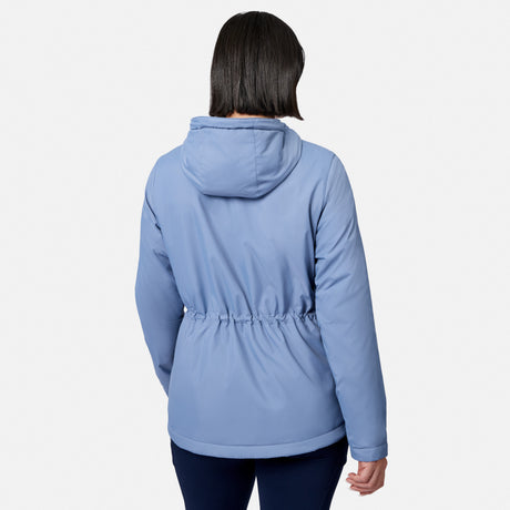 A woman with short dark hair is seen from the back wearing the Free Country Women’s Anorak Windshear Jacket in light blue, featuring a gathered waist, paired with dark pants, standing against a plain white background.