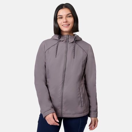 A woman with dark hair, wearing the Free Country Women’s Anorak Windshear Jacket in Zinc and dark pants, smiles while standing against a plain white background.