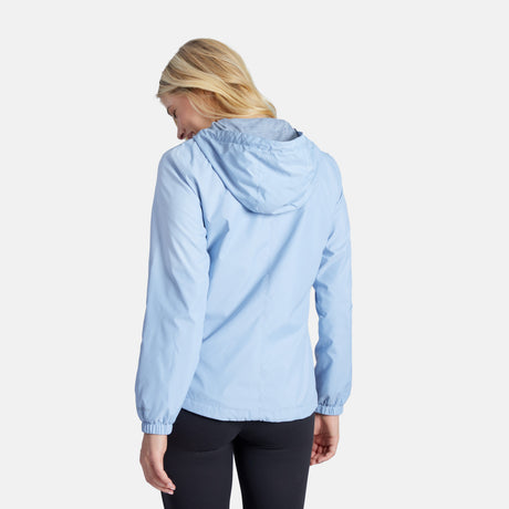 A woman with blonde hair is seen from behind wearing the Clearance Women's Outland Windshear Jacket in light blue with black leggings, standing against a plain white background.