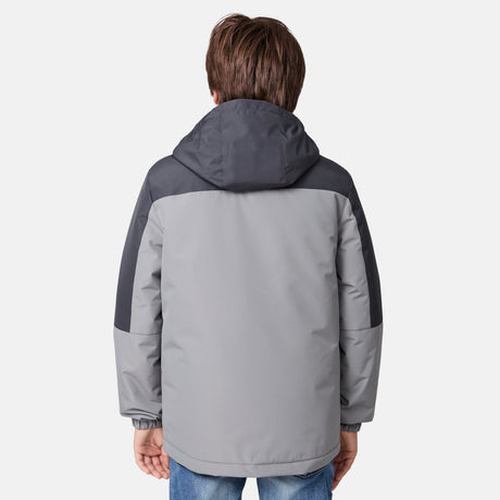 [River is wearing size M.] Young boy wearing the Free Country Boys' 3-in-1 Systems Jacket in a light grey with a hood and subtle chest pattern, smiling against a plain background.