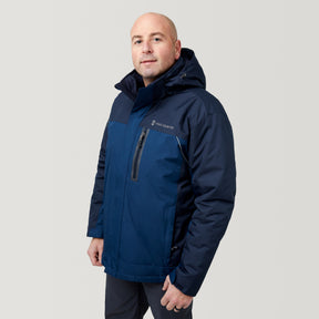 A man wears the Men's FreeCycle® Jack Frost 3-in-1 Systems Jacket by Clearance, dark blue with a hood, standing slightly to the side and looking at the camera against a plain light background.