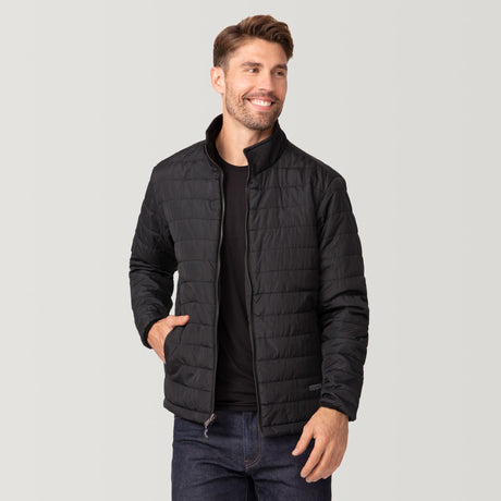 A man wears the Clearance Men's FreeCycle® Jack Frost 3-in-1 Systems Jacket in black over a black shirt and dark jeans, standing with one hand in his pocket, smiling and looking to the side against a light backdrop.