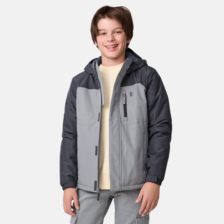 [River is wearing size M] Model wearing a two-tone gray Free Country jacket with a darker shoulder and sleeve panel, vertical zippered chest pocket, and soft hood; paired with gray pants and a light base layer for a clean, modern cold-weather look.