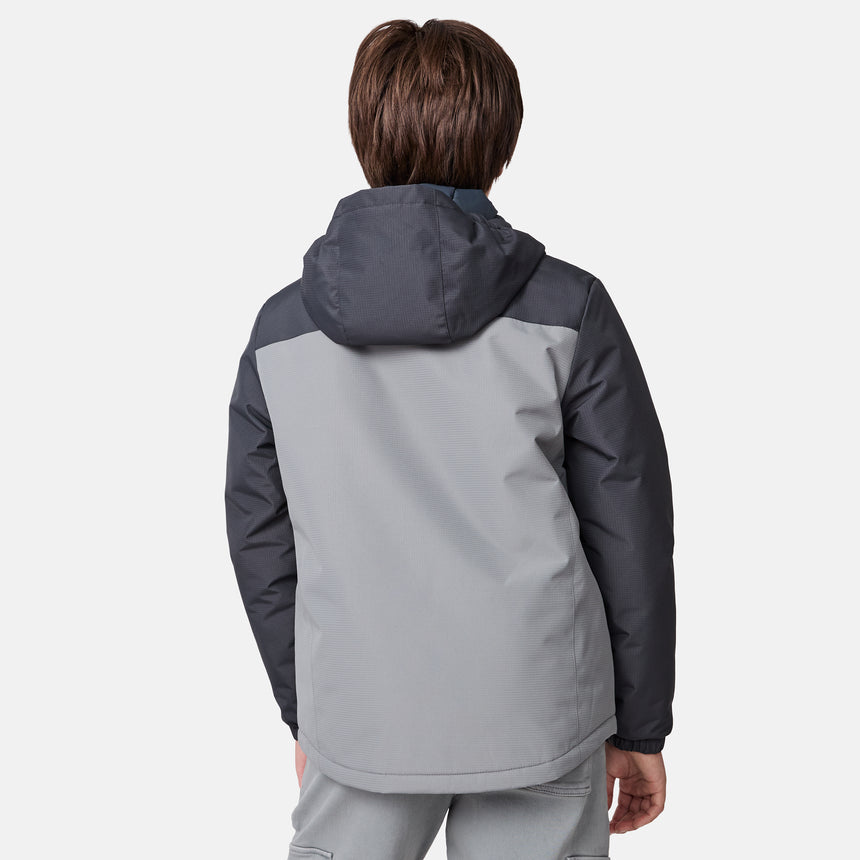 [River is wearing size M] Model wearing a two-tone gray Free Country jacket with a darker shoulder and sleeve panel, vertical zippered chest pocket, and soft hood; paired with gray pants and a light base layer for a clean, modern cold-weather look.