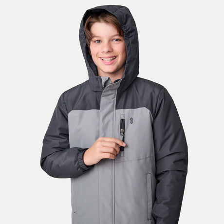 [River is wearing size M] Model wearing a two-tone gray Free Country jacket with a darker shoulder and sleeve panel, vertical zippered chest pocket, and soft hood; paired with gray pants and a light base layer for a clean, modern cold-weather look.