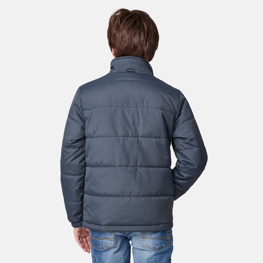 [River is wearing size M.] Young boy wearing the Free Country Boys' 3-in-1 Systems Jacket in a light grey with a hood and subtle chest pattern, smiling against a plain background.