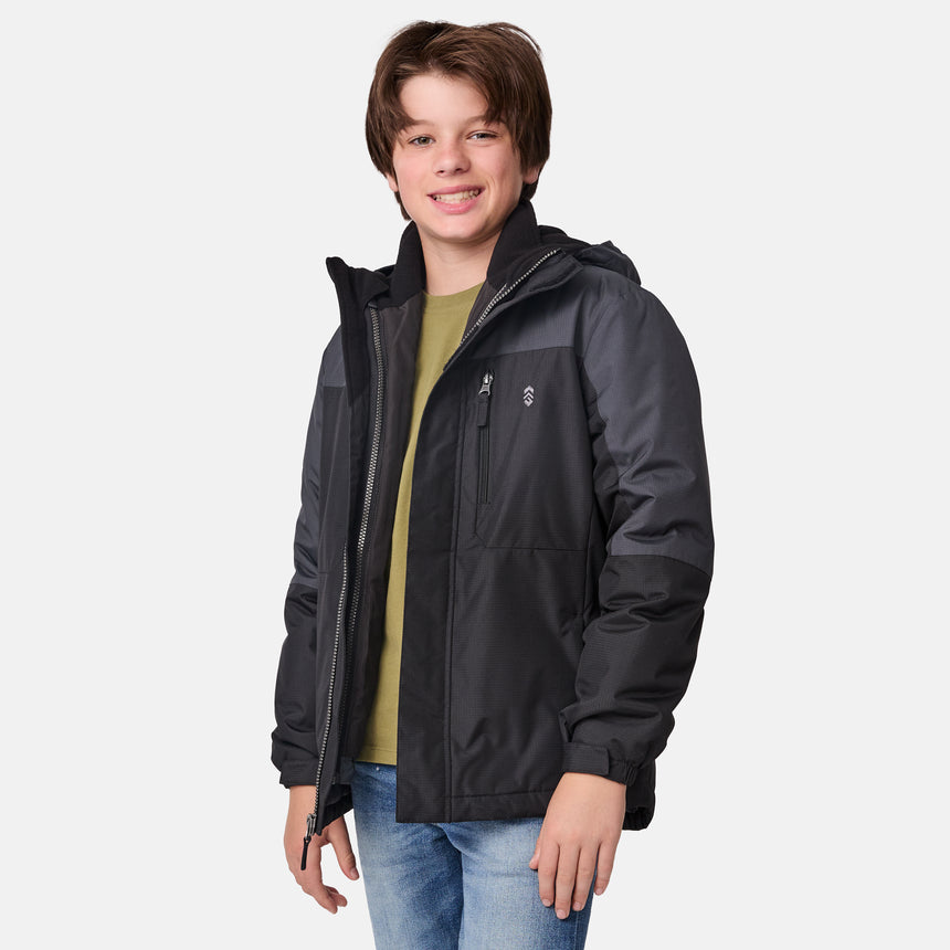 [River is wearing size M.] Boys' black 3-in-1 jacket with zip-out puffer liner and hood — versatile cold-weather system with chest logo and multiple pockets