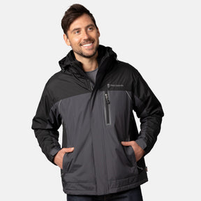 A man with short brown hair and a beard smiles with his hands in the pockets of the Men's FreeCycle® Jack Frost 3-in-1 Systems Jacket by Clearance, standing against a plain light background.