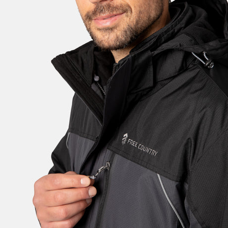 A man zips up a black and gray Men's FreeCycle® Jack Frost 3-in-1 Systems Jacket by Clearance, shown from shoulders to lips. The photo highlights the zipper, brand logo, and the jacket’s recycled REPREVE fabric.