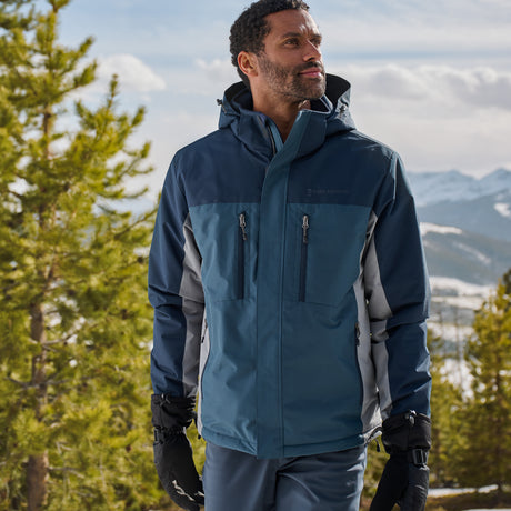 Man wearing a blue and gray jacket in a mountainous landscape