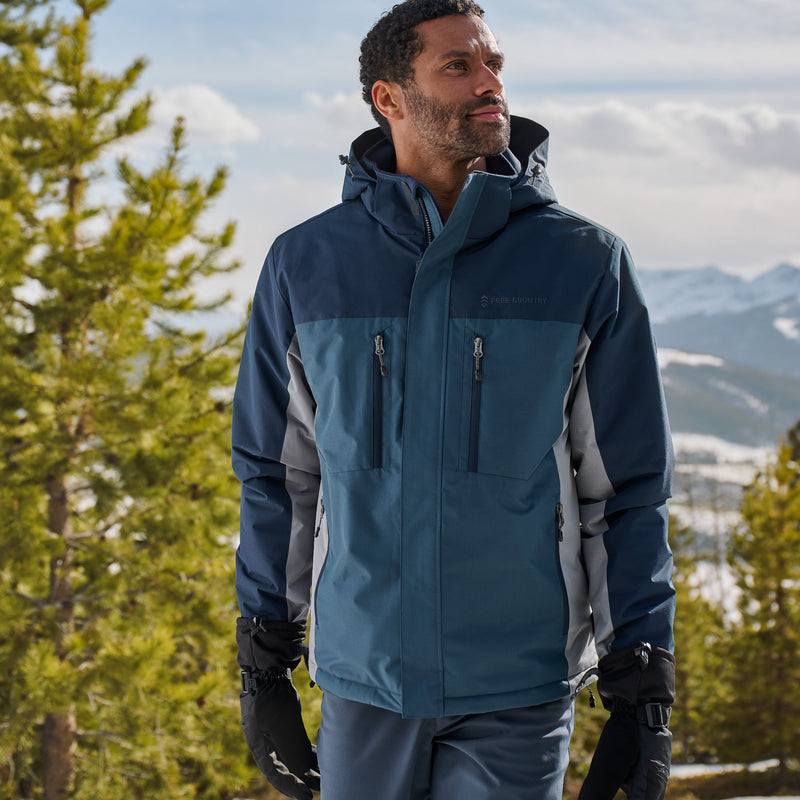 Man wearing a blue and gray jacket in a mountainous landscape