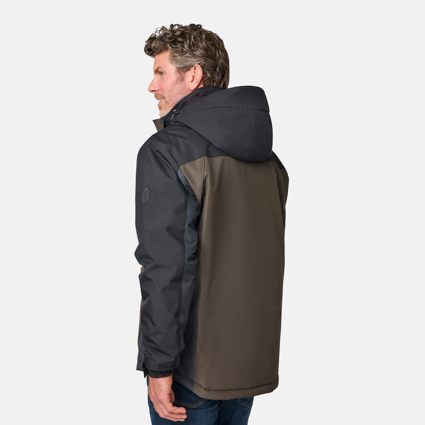 [Kolby is 6'2" wearing size M.]  "Men’s Free Country two-tone zip-front jacket with black upper section and olive green lower panels—features dual vertical zippered chest pockets, side hand pockets, and attached hood. Layered over a green crewneck tee and blue jeans for versatile, outdoor-ready style.