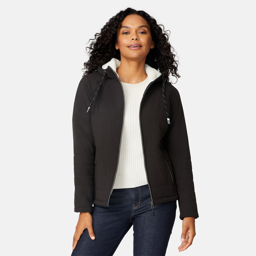 [Angelique is 5'10" wearing size S.] Women’s Free Country black hooded jacket with zip-up closure, white sherpa lining visible at the collar, and metallic drawstring tips. Features zippered side pockets and is styled with blue jeans for a clean, versatile winter look.