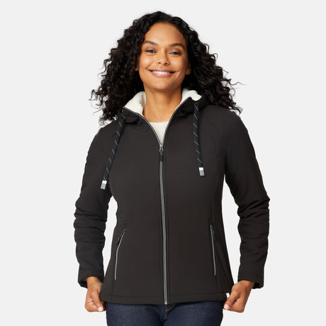 [Angelique is 5'10" wearing size S.] Women’s Free Country black hooded jacket with zip-up closure, white sherpa lining visible at the collar, and metallic drawstring tips. Features zippered side pockets and is styled with blue jeans for a clean, versatile winter look.
