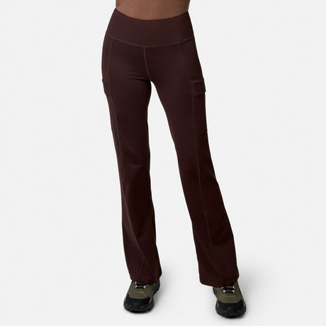 A person models Free Country Women’s Trail 2 Town Flare Pants in Espresso, featuring visible seams and side pockets, paired with olive green and black sneakers against a plain white backdrop—ideal for any outing.