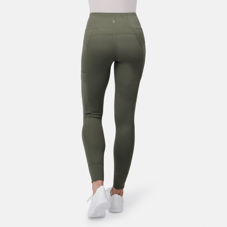 A person is seen from the back wearing Free Country Women's Trail 2 Town Legging in high-waisted olive green, featuring a high rise waistband and side pockets, paired with white sneakers, set against a plain white background.