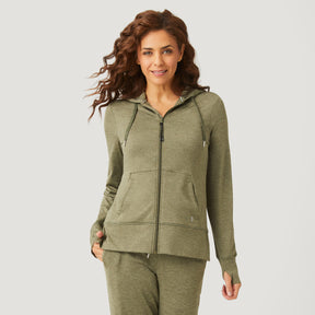 A woman with wavy brown hair wears the Clearance Women's Free 2 Go Out Zip Hoodie in olive green, featuring a front pocket, paired with four-way stretch shorts, standing against a light background and smiling at the camera.