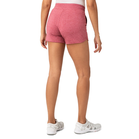 A person is shown from the waist down, wearing Clearance Women’s Free 2 Go Out Short in pink with a petal hem and four-way stretch, paired with a white top and sneakers, against a plain white background.
