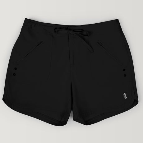 The Free Country Women's 5" Bermuda Board Short features a drawstring waistband, four-way stretch fabric, zippered side pockets, decorative buttons, and a small reflective logo on the front left leg. Shown on a plain light background.