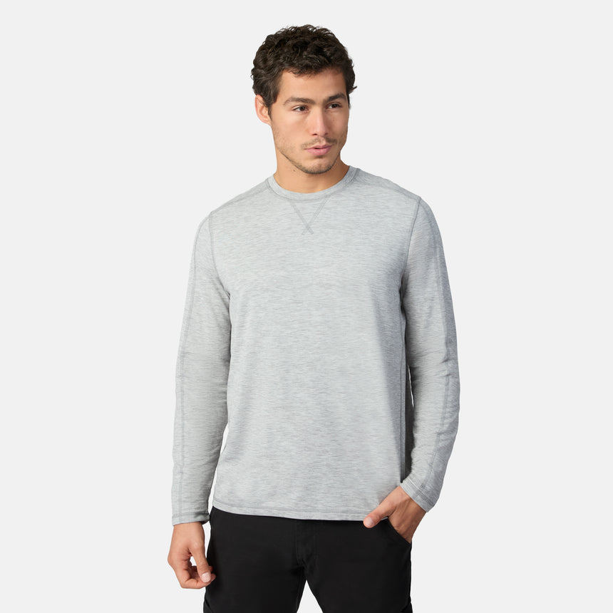 [Model is wearing size M.] A man wearing a light gray long-sleeve crewneck shirt and black pants, standing against a light gray studio background.