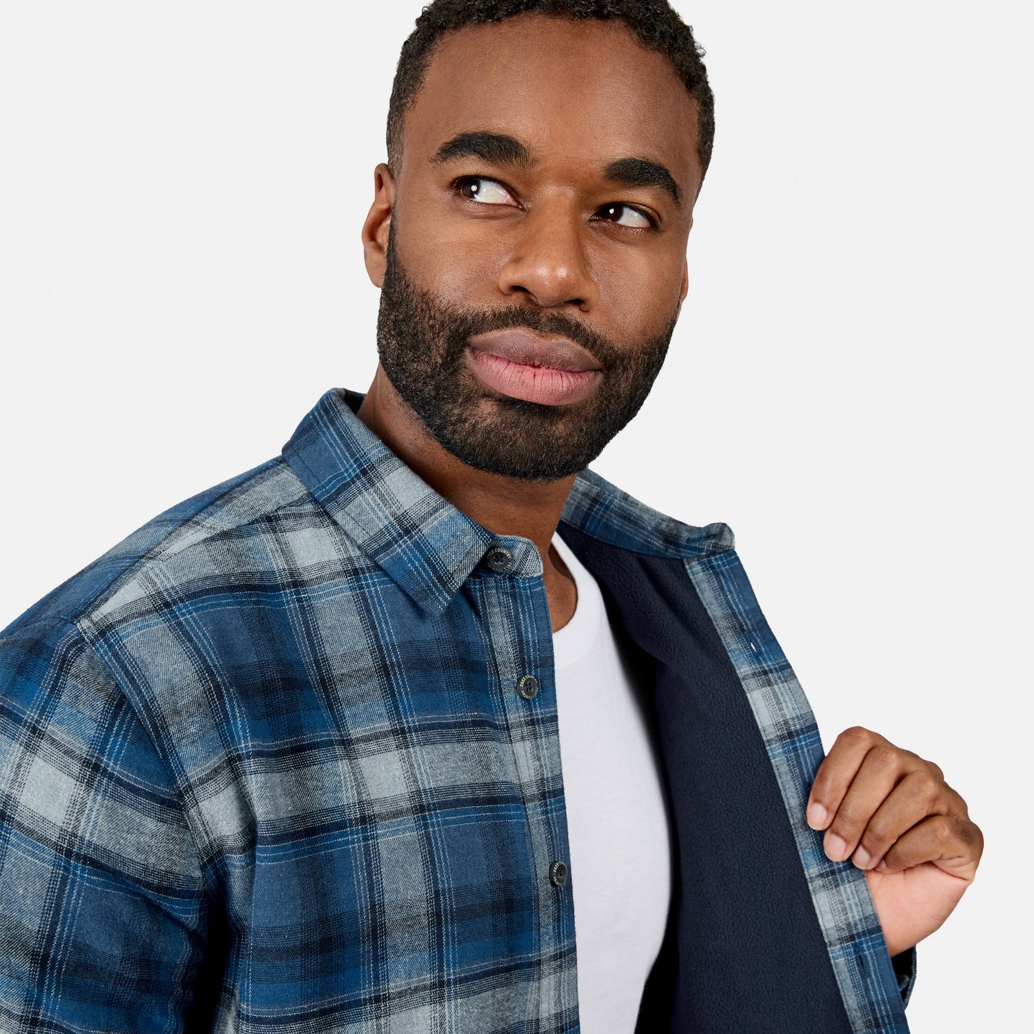 [Model is wearing size M.] Close up of man wearing blue plaid fleece lined flannel shirt with navy lining visible.