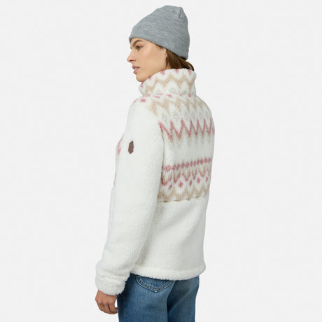 A woman in a gray beanie and blue jeans wears the Free Country Women’s Sierra Butter Pile® Zip Up Jacket—white with pink and beige geometric details—against a white background, looking to the side. Ideal lightweight warmth for chilly days.