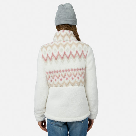 A person in a gray beanie and blue jeans models the Free Country Women’s Sierra Butter Pile® Zip Up Jacket, showcasing its cozy, lightweight warmth and stylish white and pink pattern against a plain white background.