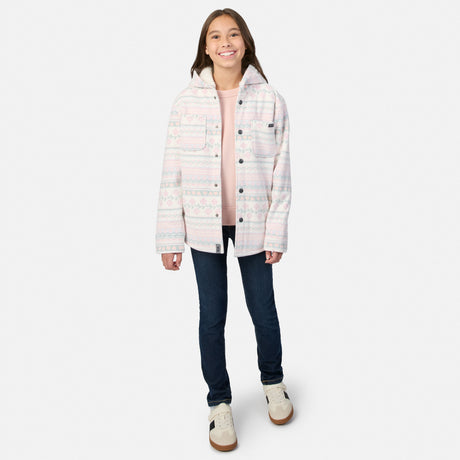 A girl wearing a Free Country Girls’ Chill Out Fleece Shirt Jacket in a plaid print with sherpa lining, a pink long-sleeve shirt, dark blue jeans, and sneakers.