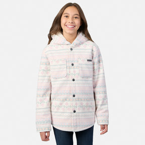 A smiling girl wears a cream-colored Girls’ Chill Out Fleece Shirt Jacket featuring a pink and green plaid print, sherpa lining, and a hood.