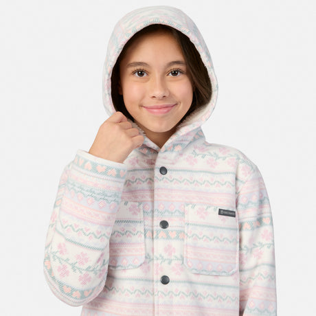 A girl wears a Girls’ Chill Out Fleece Shirt Jacket, a hooded, button-up fleece with a white, pink, and blue Fair Isle-style print and sherpa lining.