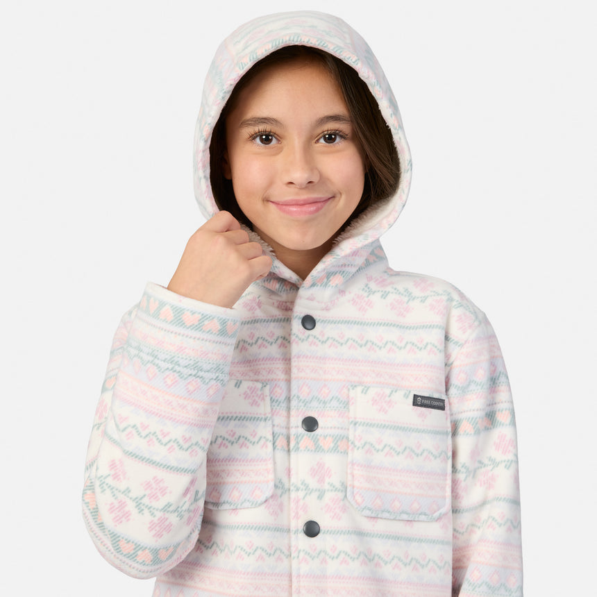 A girl wears a Girls’ Chill Out Fleece Shirt Jacket, a hooded, button-up fleece with a white, pink, and blue Fair Isle-style print and sherpa lining.