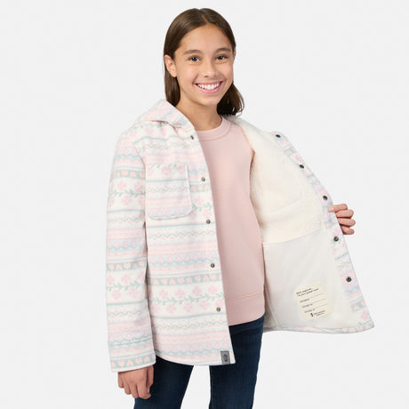 A smiling girl wearing an open, plaid print Girls’ Chill Out Fleece Shirt Jacket that reveals its interior sherpa lining and a name label.
