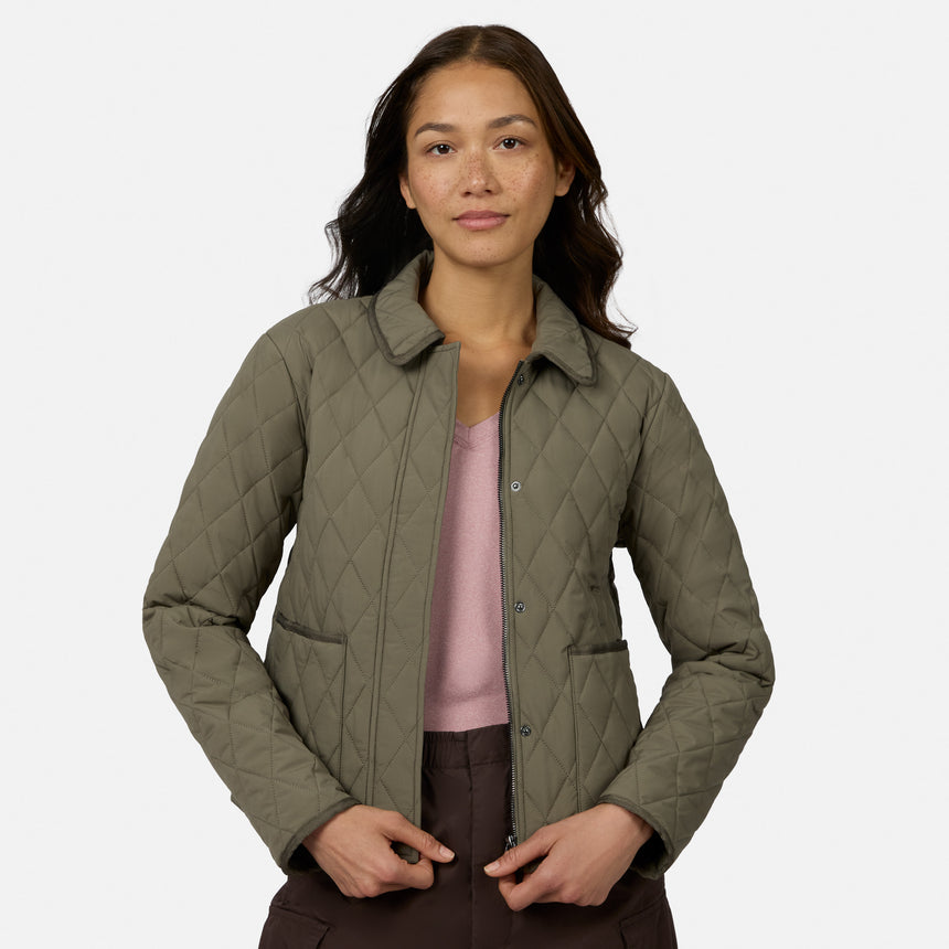 [Model is wearing size S.] A woman modeling a quilted olive green jacket over a dusty pink top and dark brown pants, photographed against a clean light gray studio background.