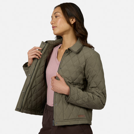 [Model is wearing size S.] A woman wearing an olive green quilted jacket over a pink top and dark brown pants, shown from the waist up against a light gray studio background.