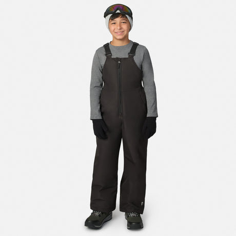 Young skier in a black half Pike ski bib pant with adjustable straps and goggles resting on the head