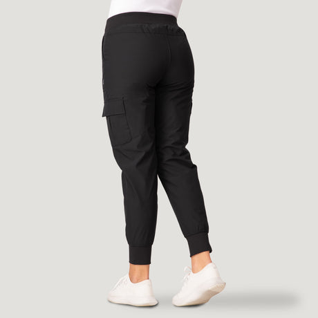 Person wearing black Free Country Women’s Get Out There Fleece Lined Jogger and white sneakers, shown from the back against a plain light gray background.
