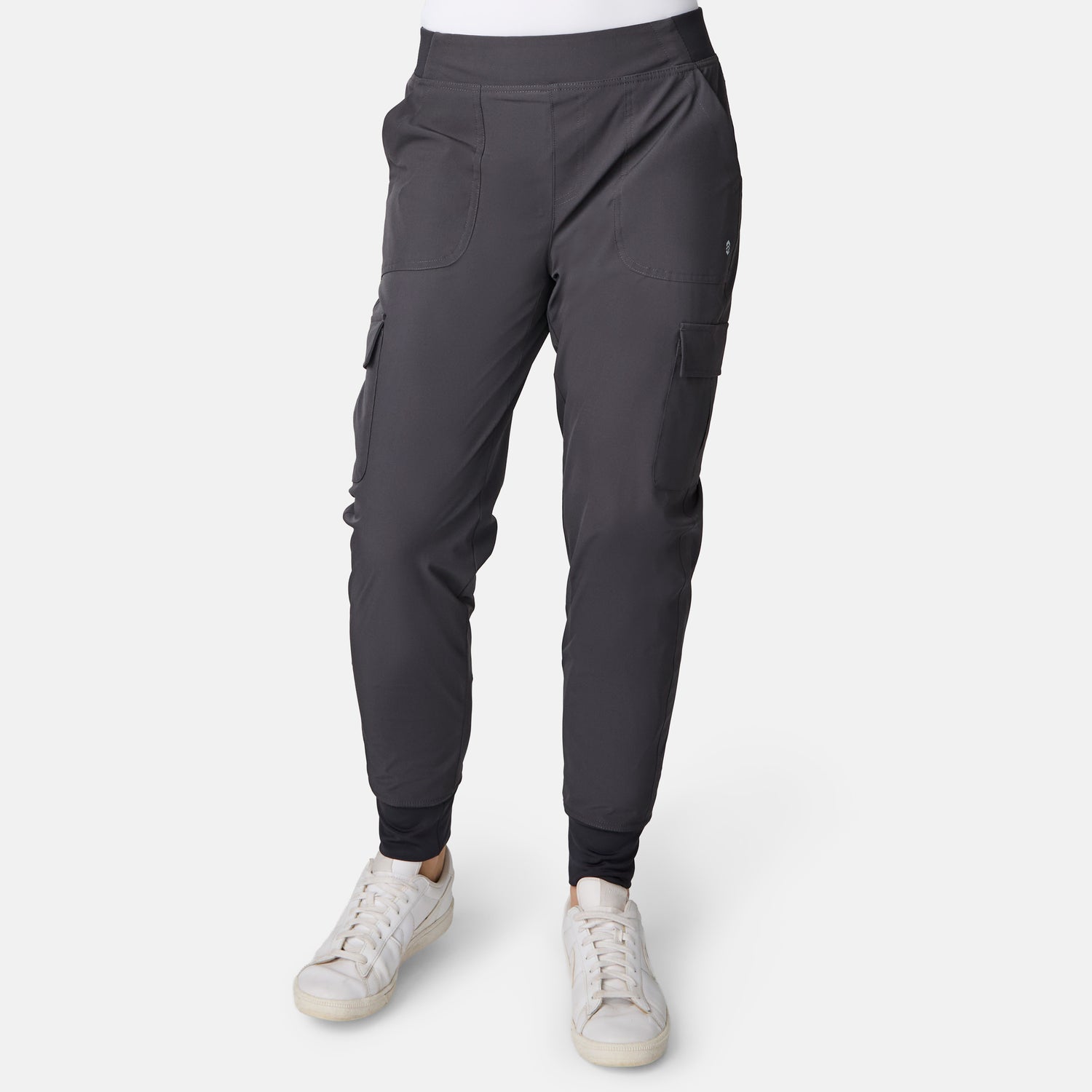 Person wearing dark gray Free Country Women’s Get Out There Fleece Lined Jogger with multiple pockets and white sneakers, standing against a plain white background. Upper body is not visible in the image.