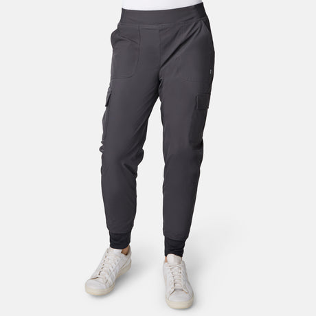 Person wearing dark gray Free Country Women’s Get Out There Fleece Lined Jogger with multiple pockets and white sneakers, standing against a plain white background. Upper body is not visible in the image.