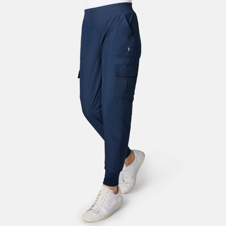 Woman wearing Free Country Women’s Get Out There Fleece Lined Jogger in Midnight with side pockets and white sneakers, standing against a plain white background.