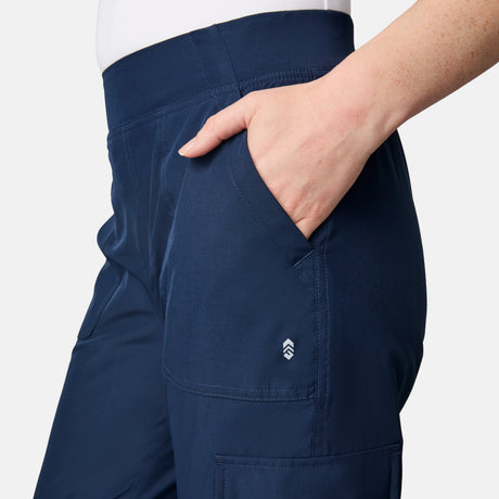 A woman wears Free Country’s Women’s Get Out There Fleece Lined Jogger in navy, featuring visible stitching, a small white logo by the pocket, and her right hand tucked in. Only her waist to mid-thigh is visible.
