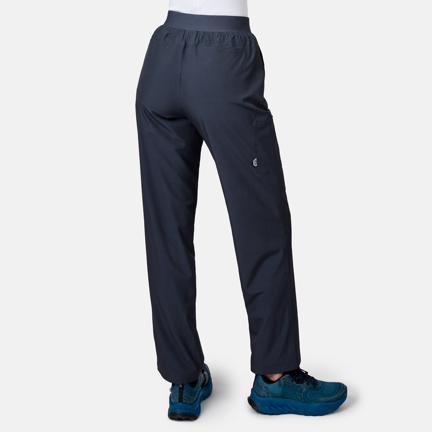 A woman wears Free Country Women’s Get Out There Fleece Lined Pants in dark gray with an elastic waistband and right-side flap pocket, paired with blue athletic shoes, shown from the back against a plain light gray background.