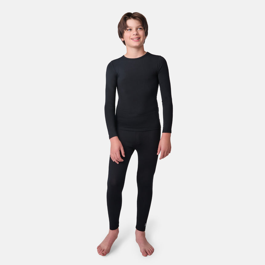 Child wearing a black long-sleeve base layer shirt and black base layer pants on a white background
