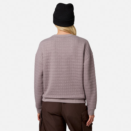 A person wears a textured mauve Free Country Women’s UltraFill Fleece Crew Neck Pullover Top with brown pants and a black beanie, standing with their back to the camera against a plain white background.