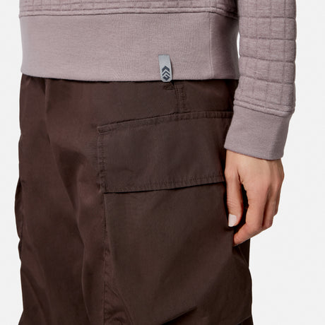 A person wears a textured, light purple Free Country Women’s UltraFill Fleece Crew Neck Pullover Top and brown cargo pants, with one hand resting by their side near the large pocket.