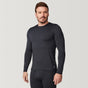 A man wearing the Free Country Men’s Microtech® Heat Cocarber® Coffee Base Layer Top in black, along with matching black leggings made from recycled materials, stands against a plain light background, looking slightly to the side.