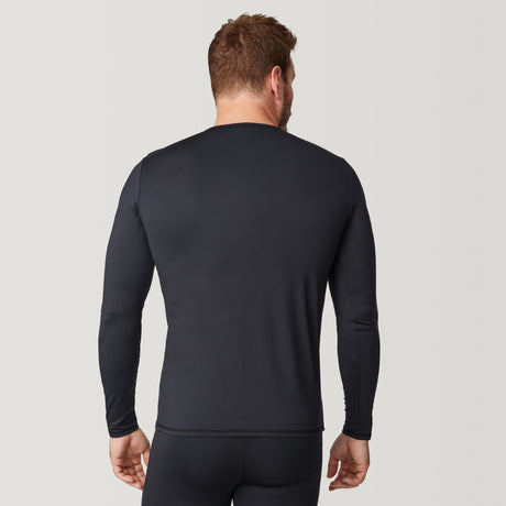 A man stands facing away against a plain light background, wearing the Free Country Men’s Microtech® Heat Cocarber® Coffee Base Layer Top from the 2-Pack, a fitted, long-sleeve black shirt made with recycled materials, paired with matching black pants.