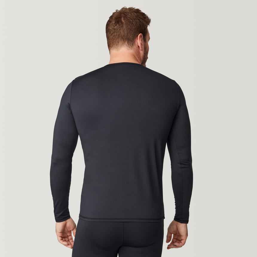 A man stands facing away against a plain light background, wearing the Free Country Men’s Microtech® Heat Cocarber® Coffee Base Layer Top from the 2-Pack, a fitted, long-sleeve black shirt made with recycled materials, paired with matching black pants.