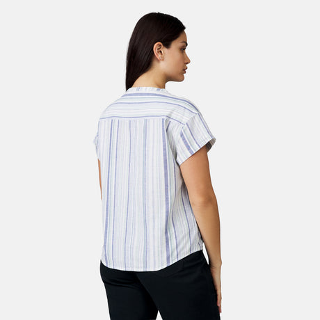 A woman with long dark hair is seen from the back wearing the Free Country Women's Easy Breezy Shirt, a pastel striped cotton linen short-sleeve top, paired with black pants against a plain white background.